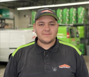 Male with hat standing in front of SERVPRO vehicles