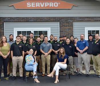 Our team poses in front of a wall decorated with SERVPRO-inspired street art in our warehouse